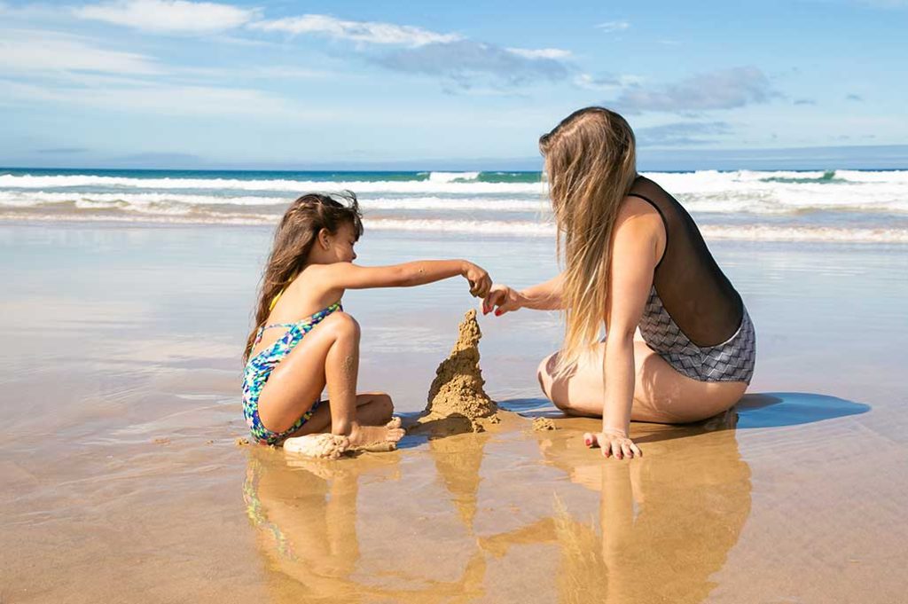 mamá con niña jugando en la arena